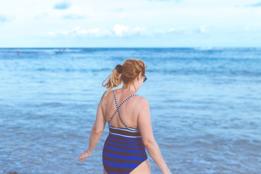Woman in a bathing suit getting into the ocean 