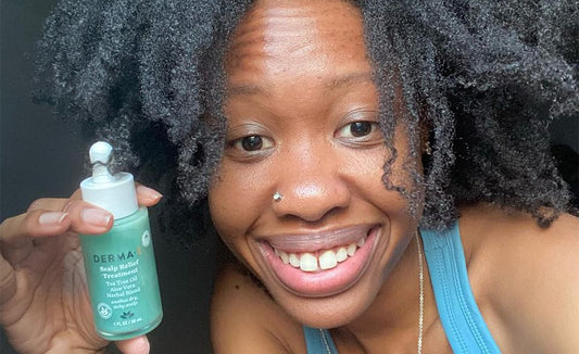 Beautiful black woman with typed 4B hair holding a green bottle of derma e's scalp relief serum and smiling