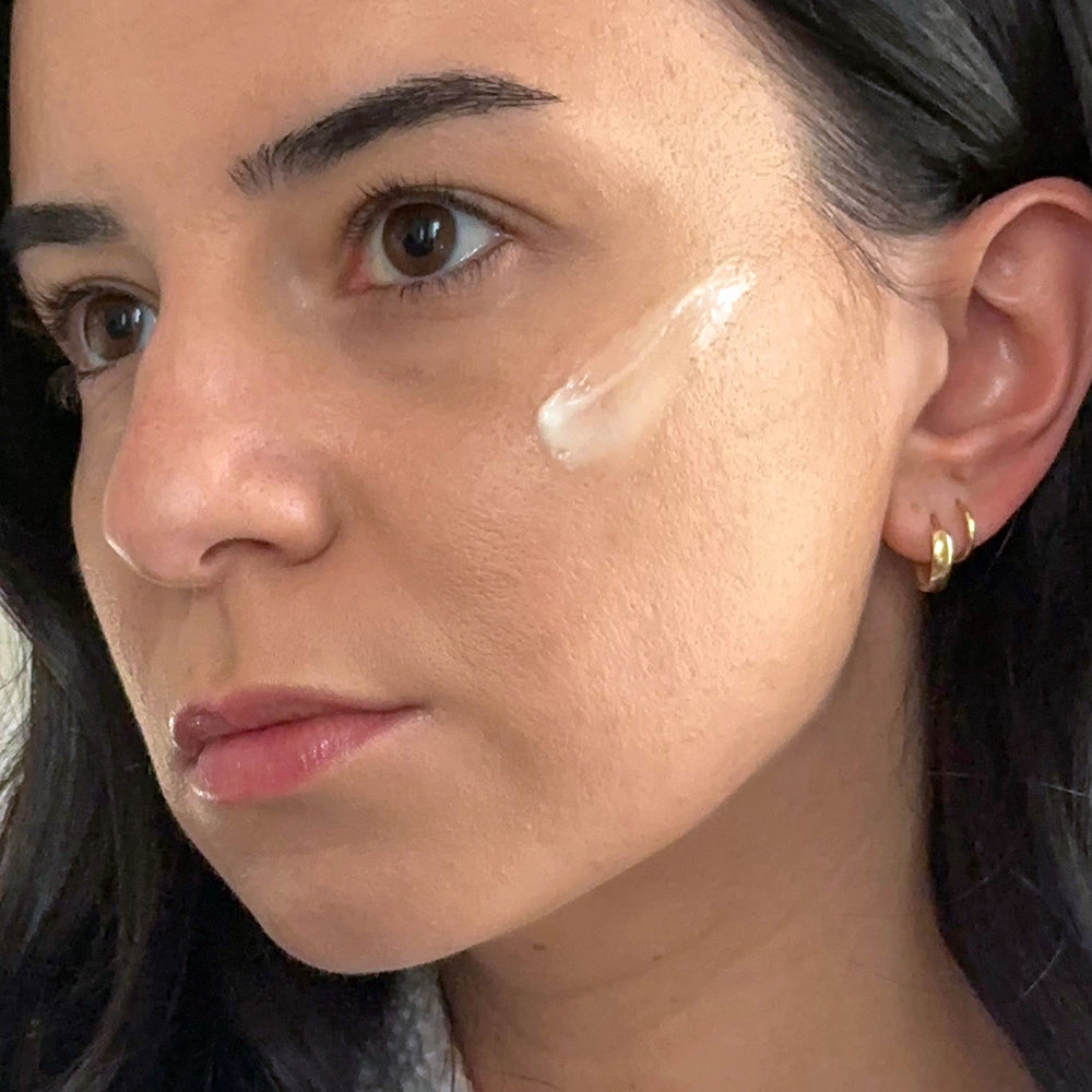 Close-up of a woman's face with a skincare product applied to her cheek.