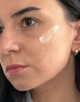 Close-up of a woman's face with a skincare product applied to her cheek.
